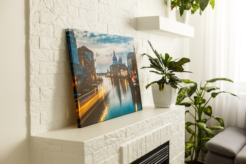 An Unframed Canvas Print Leaning Against a Fireplace Mantel